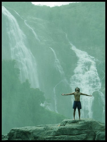 man with arms open at waterfall