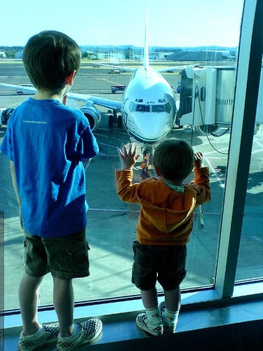 two boys at airport looking at airplane